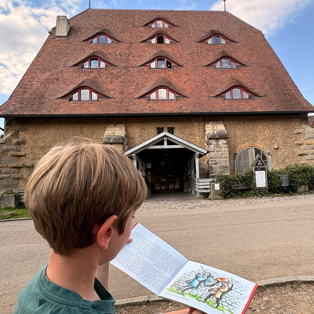Spannende Infos im Kinderstadtf&uuml;hrer vor der Ro&szlig;m&uuml;hle in Rothenburg lesen